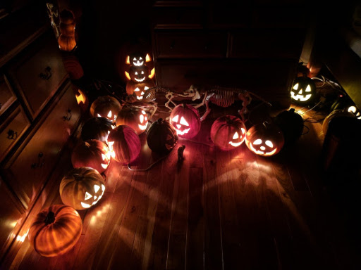 Numerous fake jack o'lanterns glowing in a darkened room.